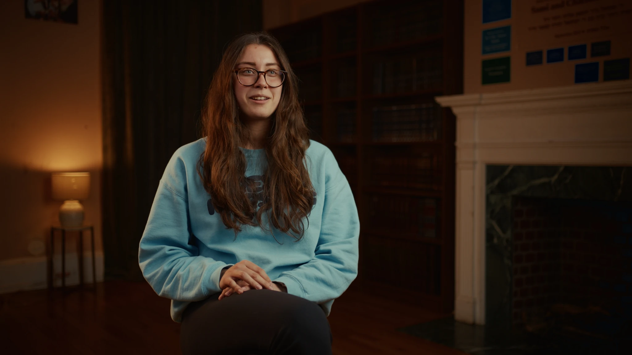 A seated interview beside a fireplace and a softly glowing lamp
