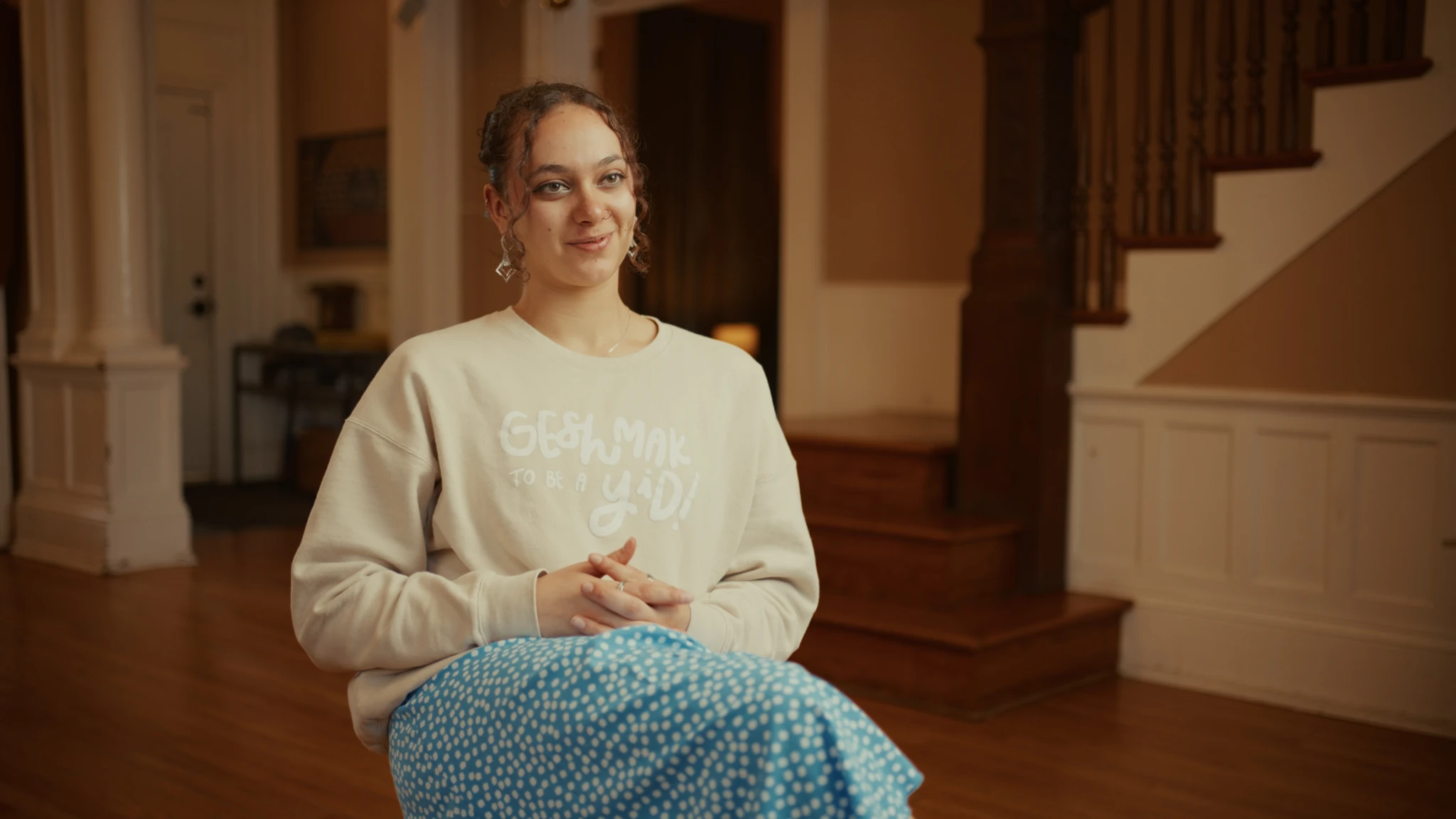 A seated interview with a wooden staircase in the background