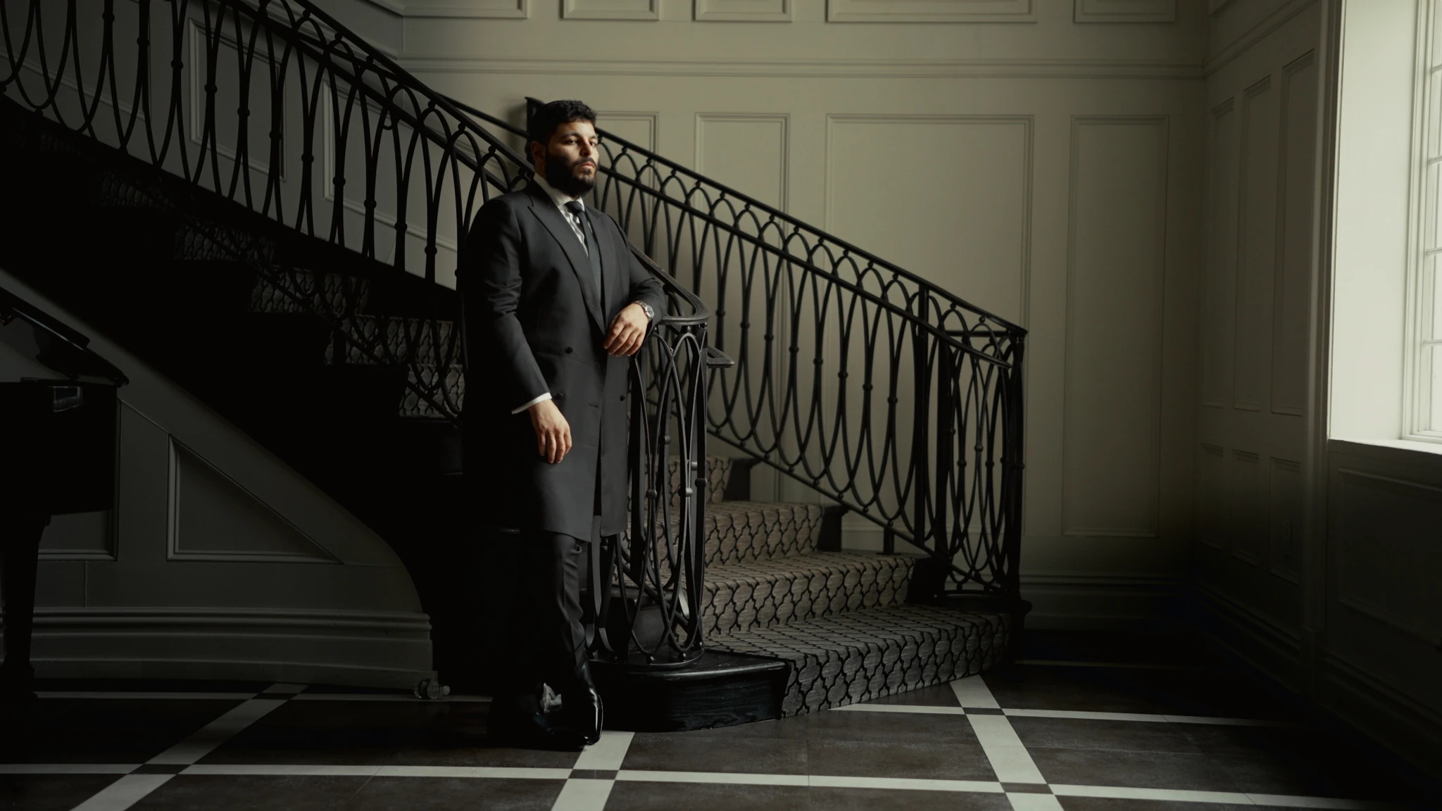 A groom standing beside a curved staircase